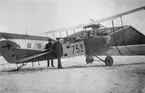 Flygplan Albatros SW 20 nr 752 står framför hangarer, vintertid omkring 1918-1924. Tre militärer står vid flygplanet.