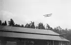 Flygplan Albatros flyger lågt över C- och D-hangarerna på Flygkompaniets verkstäder på Malmen, omkring 1920.