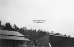 Flygplan Albatros flyger lågt över C- och D-hangarerna på Flygkompaniets verkstäder på Malmen, omkring 1920.