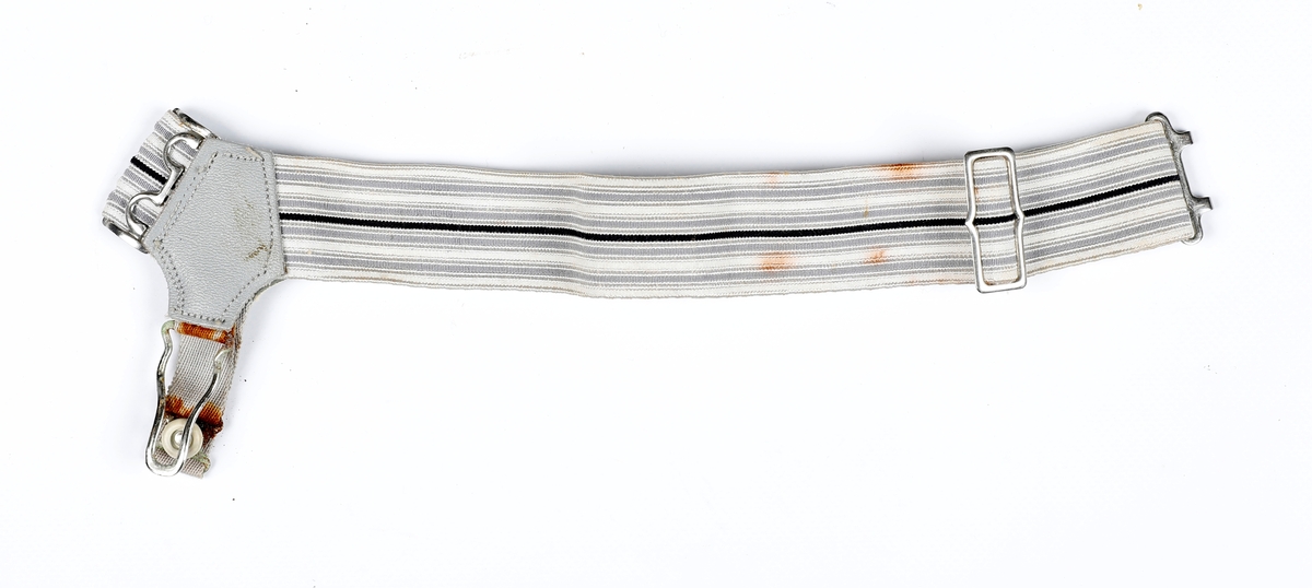 En enkelt strømpeholder til herre, andre del av par mangler. Lys grå med mørkere grå striper og en mørk stripe i midten. Grå lærbit og metall hekter og spenner. Knapp laget av plast.