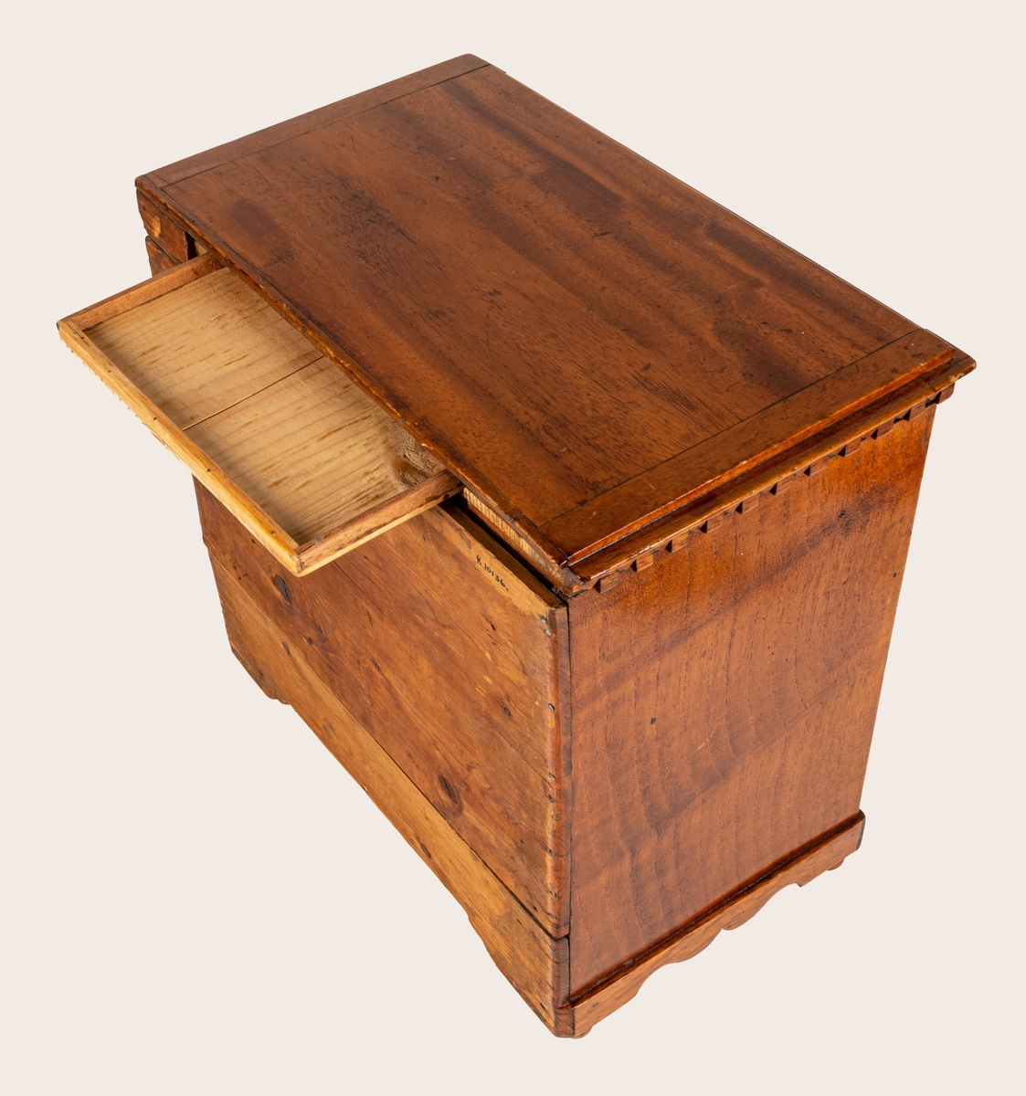 Sybyrå, barock typ, med tandning under skivans kanter. Miniatyrbyrå, med tre draglådor med fanér, delvis i rutmönster. Gjutna bronshandtag. Kulfötter. Obs. en liten smal låda upptill på byråns baksida.