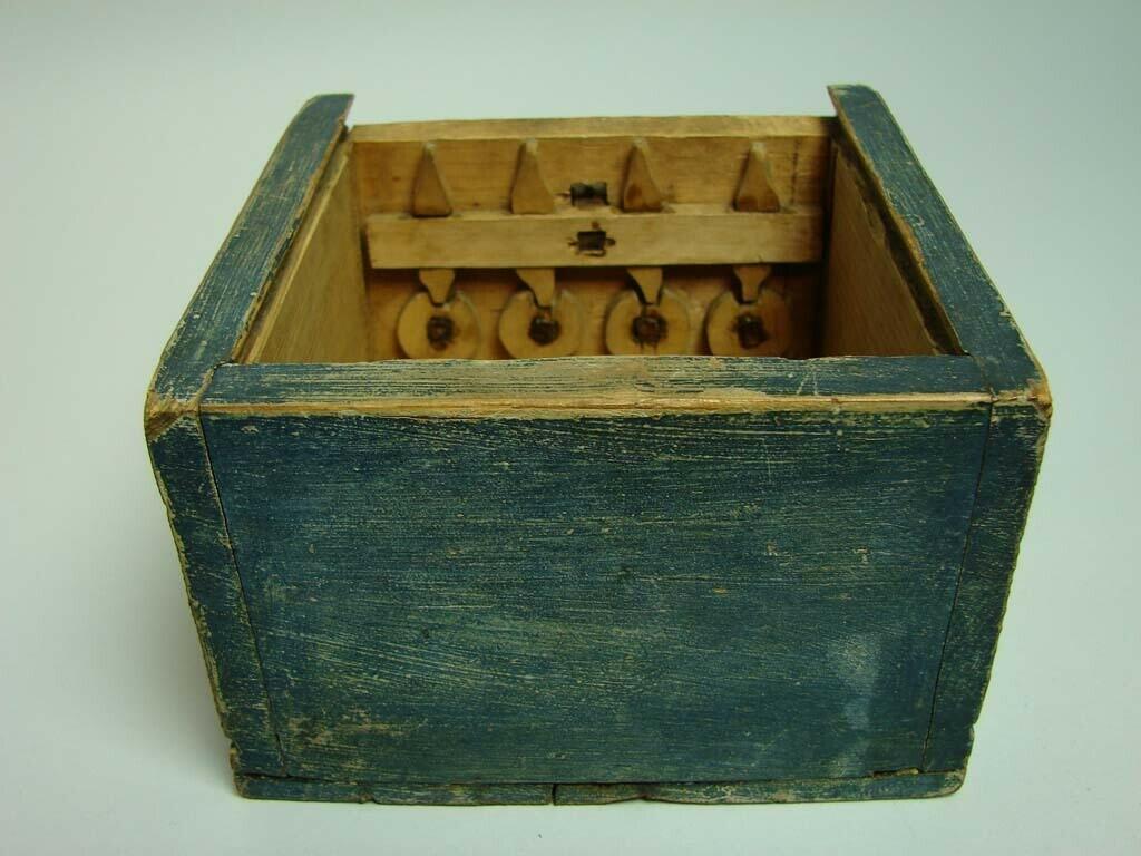 Skrin i furu med skjutlock. Blåmålat. Hopfogat med träplugg, utanpåliggande, pluggad botten. Konstlås; på insidan fyra uppskjutande spetsar i trä fassatta i regel som skjuts uppåt via reglage på skrinets framsida. I uppskjutet läge passar spetsarna in i motsvarande hål i lockets undersida, vilket håller skrinet låst. Regeln hålls kvar i låst position via fyra hjul som styrs av från utsidan av fyra, nu förlorade, knappar. Teckning på lockets insida av två röda tuppar samt otydbar.