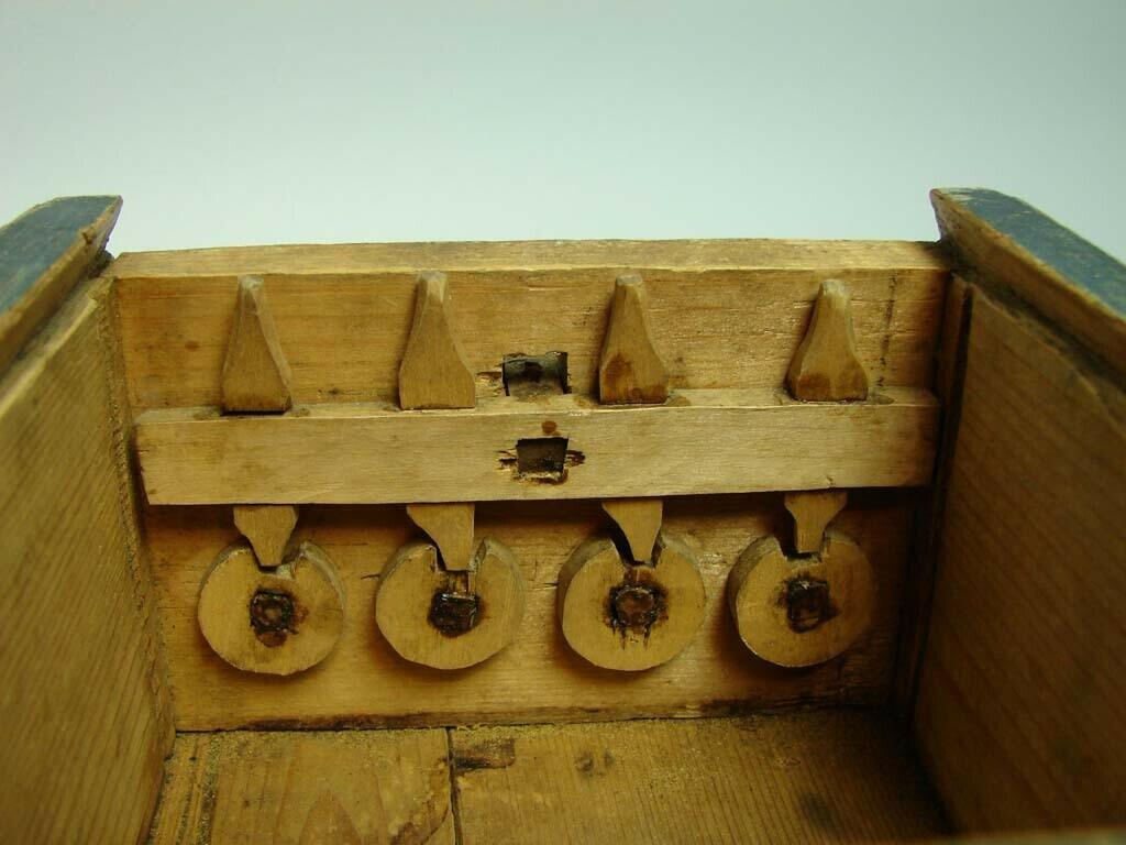 Skrin i furu med skjutlock. Blåmålat. Hopfogat med träplugg, utanpåliggande, pluggad botten. Konstlås; på insidan fyra uppskjutande spetsar i trä fassatta i regel som skjuts uppåt via reglage på skrinets framsida. I uppskjutet läge passar spetsarna in i motsvarande hål i lockets undersida, vilket håller skrinet låst. Regeln hålls kvar i låst position via fyra hjul som styrs av från utsidan av fyra, nu förlorade, knappar. Teckning på lockets insida av två röda tuppar samt otydbar.