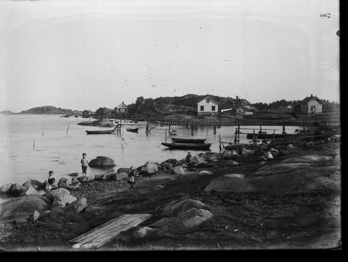 Havnemiljø med barn som leker i strandkanten.