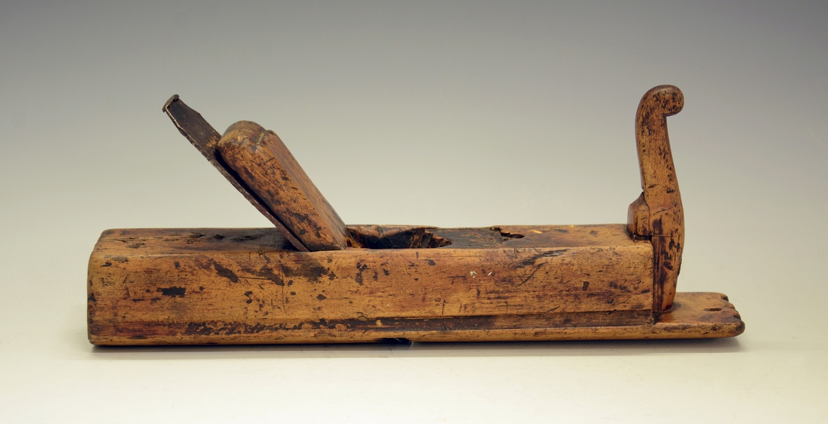 Høvel. Fra protokollen: Holkilhøvel av bjørk, rund sole. Staalbladet med konveks egg. Stokken hev fuglehalslaga handtak framme. Merke ved tornanga: PB. (R. Berge)