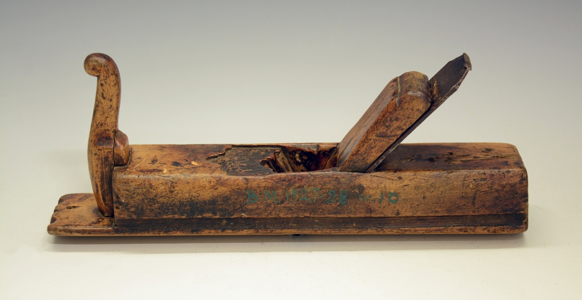 Høvel. Fra protokollen: Holkilhøvel av bjørk, rund sole. Staalbladet med konveks egg. Stokken hev fuglehalslaga handtak framme. Merke ved tornanga: PB. (R. Berge)