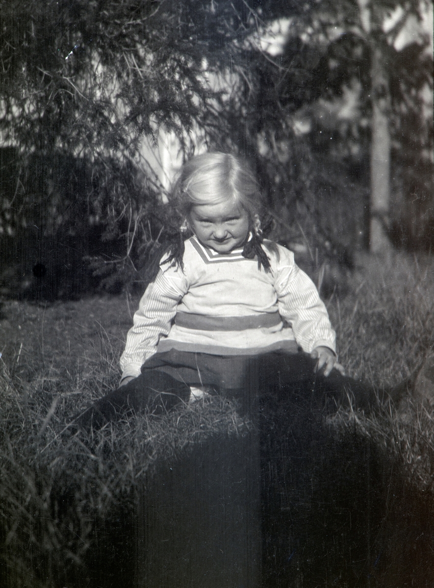 Andrea Margrethe Gjestvang, Gift Glærum (1914-1993) sittende på gresset i hagen på Nordre Ottestad. Stange.