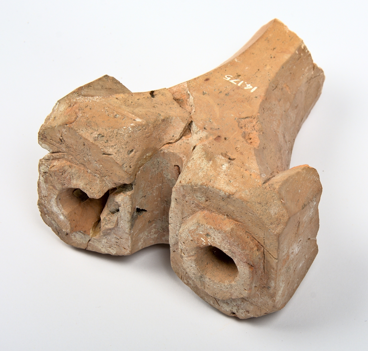 Ljusstake av oglaserat tegel. Ljusstaken har två armar med en urgröpning för ljus vardera. Skaftet är avslaget och saknas - till föremålet hör en modern rekonstruktion som visar hur skaftet kan ha sett ut; se bilder.