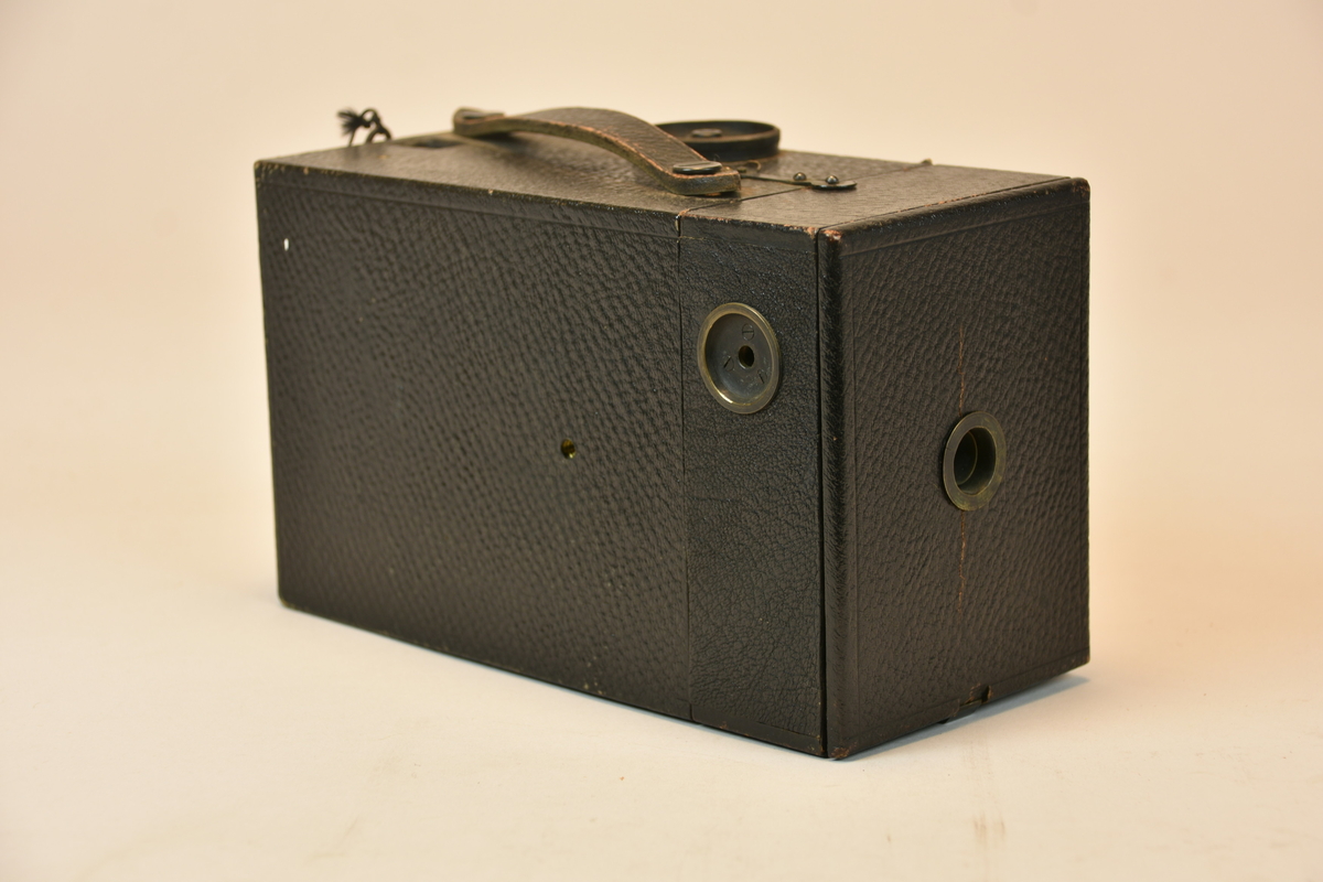 Lådkamera Kodak Junior No. 3. Objektivskydd av filt. Magasin för rullfilm, 100 exponeringar. För att ställa in exponeringstiden och bländare fälldes fronten fram med hjälp av den lilla öglan.
Lös skruv medföljer.
