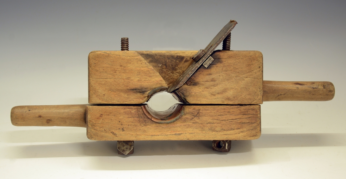 Naglelod. Redskap til å dreie skipsnagler av tre. Fra protokollen: "Nagledreie", reidskap til aa dreie skipsnaglar. Av eik (?), ihopsett av tvo rektangulære klossar (med handtak i eine enden), i principet ein hyvelstokk som i øvre tykkare halvpart hev hyveltann, og som heng ihop med undare halvpart med tvo jarnskruvar, mest som ei bokbindarklembe. Tvert igjenom baae klossane (med ei skore i kvar) gjeng eit koniskt laga hol, med koparskodde sidur, i dette holet vert trenaglen tilmaksla, i di hyvetorni gjeng inn til dette. (R. Berge)