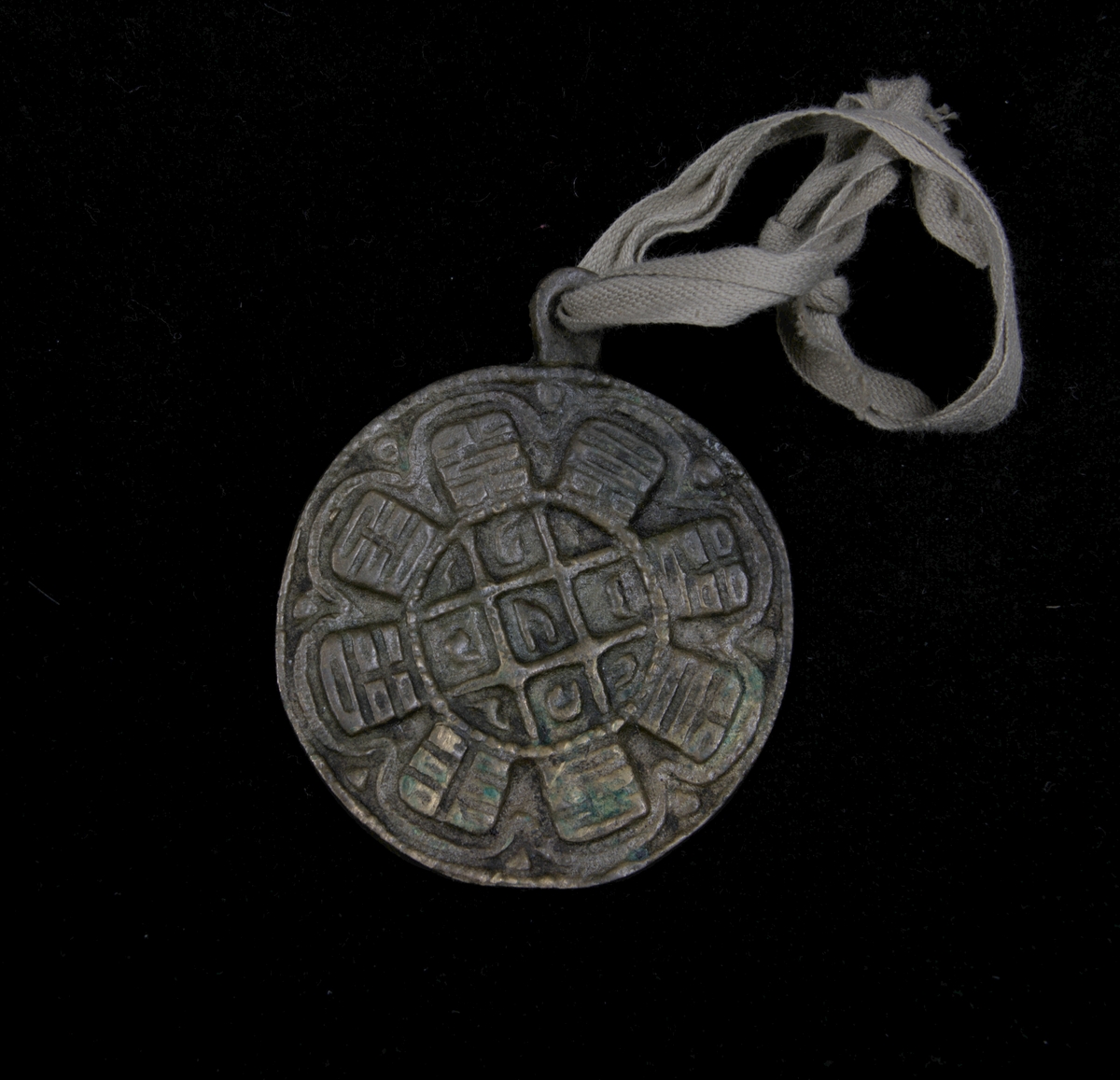 Amuletten, som tros tillhöra den tibetanska riktningen av taoismen, består av 9 centrala tecken, som ska symbolisera ett djur och en yttre ring bestående av 8 tecken. De åtta tecknen som finns i denna yttre ring, även kallat ”trigram”, är tänkta att symbolisera ett väderstreck och dess betydelse för naturen. Exempelvis kopplas tecknet för eld samman med väderstrecket syd, öst kopplas till blixt, väst kopplas till sjö och nord till vatten.

Amuletten förefaller dock att vara tillverkad upp- och nedvänd. 
Amuletten är gjuten av koppar, eller möjligen brons och tros vara tillverkad vid slutet 1800- till tidigt 1900-tal.