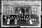 Skolklass och lärare framför skola