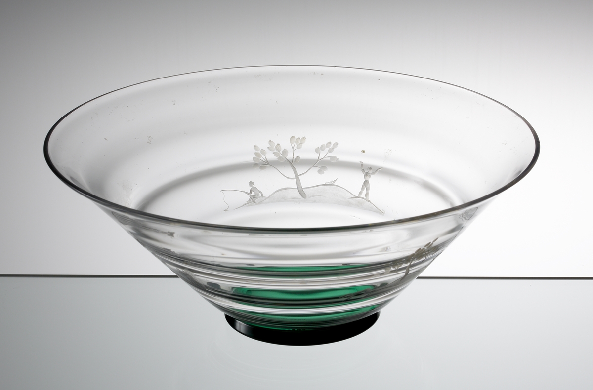 Formgiven av Nils Landberg. Konande skål med liggande optik och grön klack. Skålen graverad med tre olika ömotiv med människofigurer som fiskar, badar och har utflykt.
Ref: Gustav Abels del 2: ”Landberg 1932. Ganska goda försäljningar.”