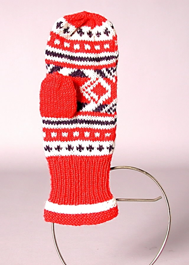 Stickad vantar i rött, vitt och blått ullgarn. Mudden resårstickning med 3 cm. rätstickning i kanten, i övrigt slätstickning.