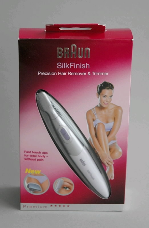 Rakapparat för kvinnor, grå och lila: "BRAUN SilkFinish Precision Hair Remover & Trimmer". Förpackad i rosa papplåda med text och bild. Bruksanvisning, två stycken skärhuvuden, två stycken trimningskammar och borste förvaras i en vit påse. 