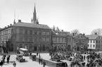 Vy över Stora torget i Linköping. I fonden bebyggelse i kvarteret Apoteket med bland andra Sahlströms bokhandel i gatuplanet. Den tygklädda konstruktionen i förgrunden daterar bilden till 1927. Där pågår förberedande arbeten för Carl Milles Folkungamonument, som kommer att vara på plats nämnda år och invigas vid årets slut.