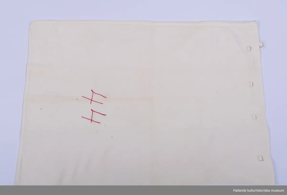 Stickpåse av vit bomull. Märkt: "44", broderat med röd tråd mitt på påsen.