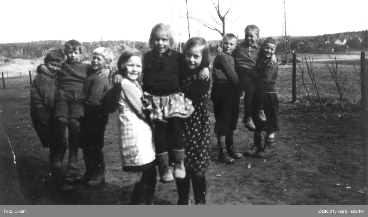 Lekende barn fra Neaskog skole i 1936 - ved Kommunelokalet. Fotografert av deres lærerinne. Fra v.: Isak Lunde, Georg Gressum, Johan Mathiesen, Malene Tangen, Else Haugård, Astrid Bøe, Ole K. Brenne, Ragnar Bergerud, Ole O. Brenne.