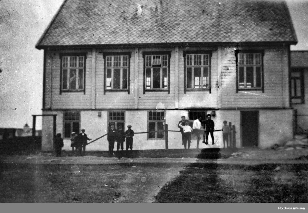 Tekst: "Ungdomshuset Breidablikk. Vårt koncertlokale i Bud." Foto ungdomshuset "Breidablikk" på Bud i Hustadvika kommune. Guttemusikkorpset var på turne til Bud og Molde påsken (5.- 6. april) 1920. Fotografier fra protokollen til Kristiansunds Guttemusikkorps i perioden 1917-1927. Protokollførere var brødrene Hans og Herlof Harstad. Protokollen er i museets privatarkiv under nr. 684. Giver av protokollen er Knut Harstad. Fra Nordmørsmusea sin fotosamling.