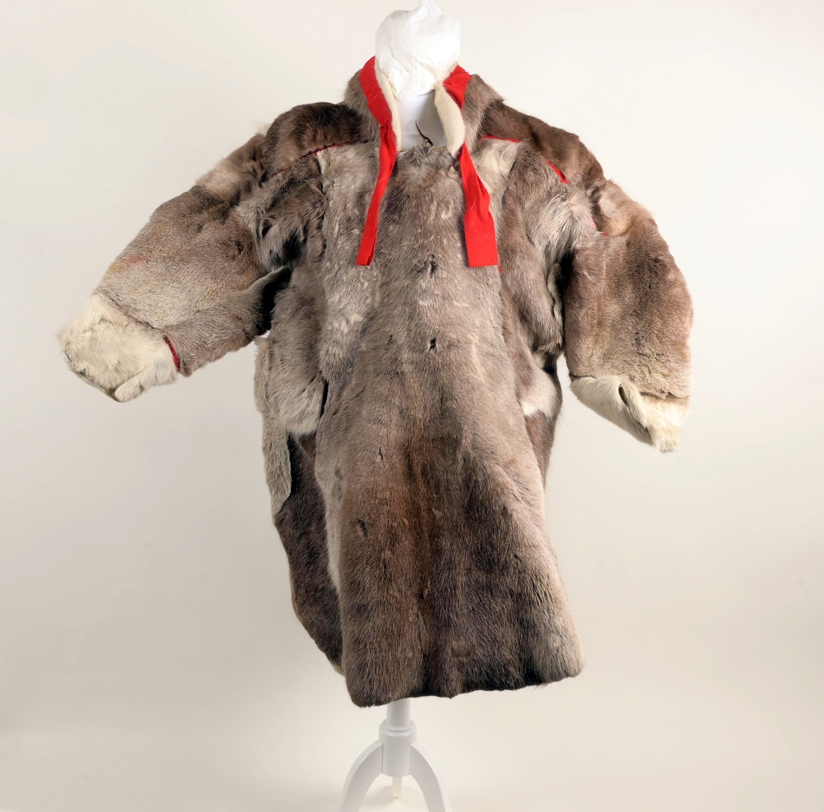 Pesk av reinsdyrskinn med bellinger, kommager og kommagbånd. Pesken har strammebånd rundt halsen. Disse er røde. På ryggen av pesken er det flere paneler. Disse er festet sammen med rødt stoff mellom panelene.
Bellingene er av reinsdyrskinn. Nederst er det påsydd klede, som er i rød tekstil. Øverst har bellingene stramming med tau. I endene av tauene er det dusker i rødt, gult og grønt. Kommagene er av reindyrskinn. Som bellingene har de snøring i toppen med tau. I enden av snøringene er det dusker.  Duskene er i råd og blått. Kommagbåndene er vevd med snøringer i begge endene. I ene ende er det lærbånd til snøring. I den andre enden er det snøringene av ull og med dusk i sine ender.