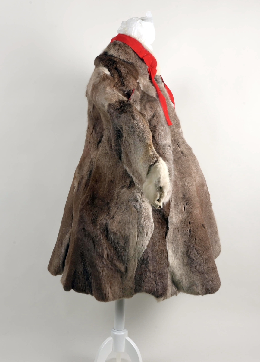 Pesk av reinsdyrskinn med bellinger, kommager og kommagbånd. Pesken har strammebånd rundt halsen. Disse er røde. På ryggen av pesken er det flere paneler. Disse er festet sammen med rødt stoff mellom panelene.
Bellingene er av reinsdyrskinn. Nederst er det påsydd klede, som er i rød tekstil. Øverst har bellingene stramming med tau. I endene av tauene er det dusker i rødt, gult og grønt. Kommagene er av reindyrskinn. Som bellingene har de snøring i toppen med tau. I enden av snøringene er det dusker.  Duskene er i råd og blått. Kommagbåndene er vevd med snøringer i begge endene. I ene ende er det lærbånd til snøring. I den andre enden er det snøringene av ull og med dusk i sine ender.