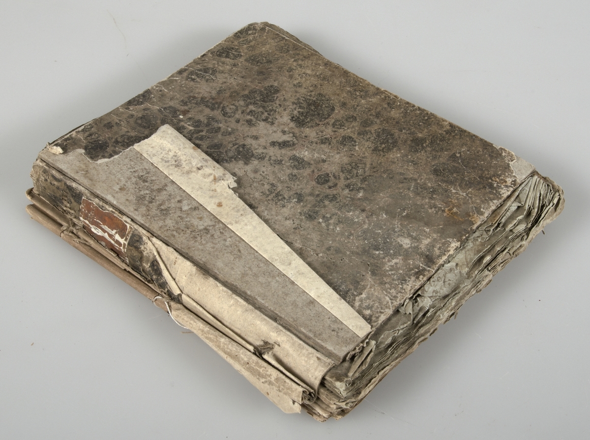 Dagbok i form av lösblad som satts ihop med tråd. Papper i blåaktig respektive gulaktig ton. Handskrivet med bläck. Pärm med brunspräckligt mönster. Inget bakstycke.