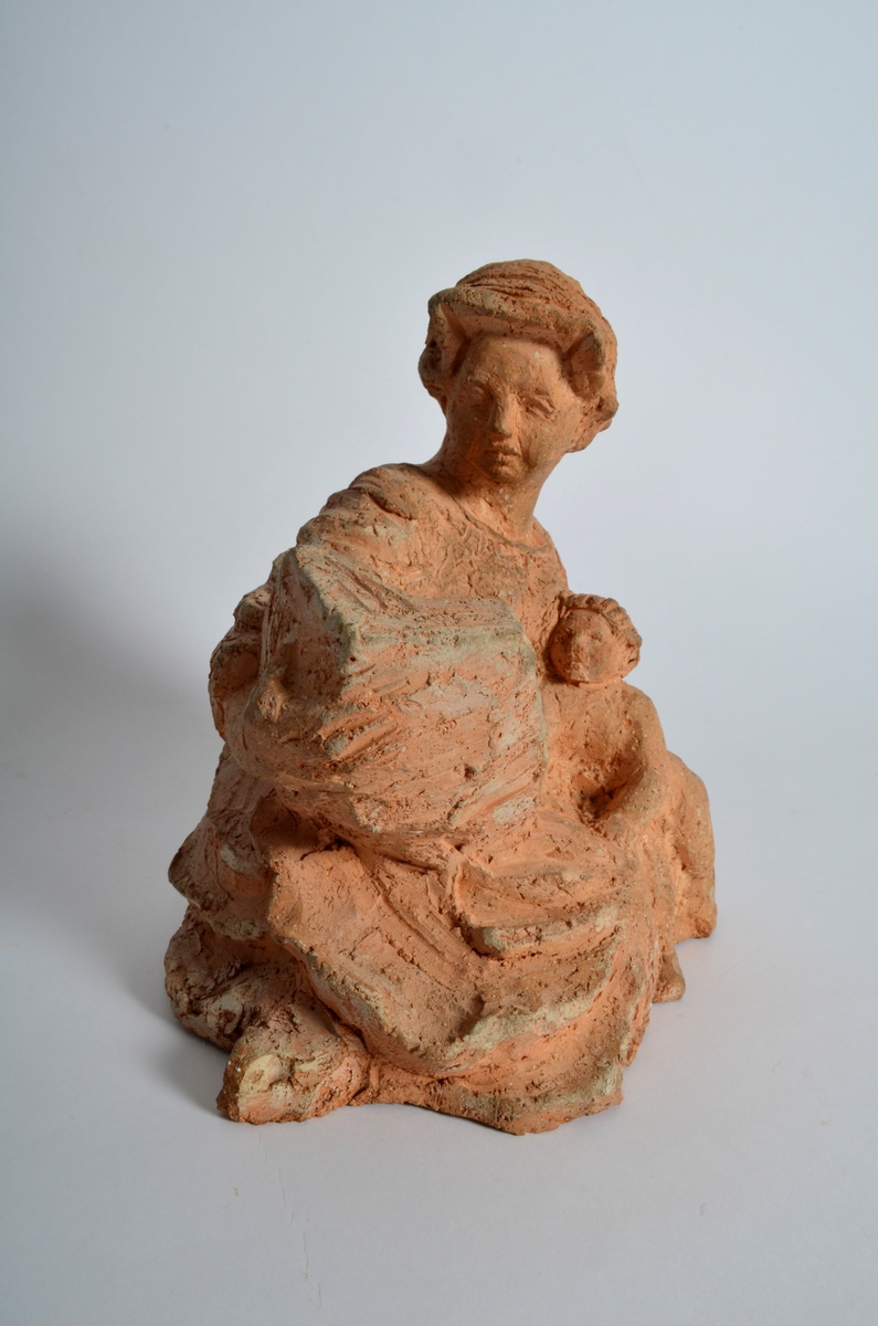 Terrakottafigur som visar ei stjande kvinne som les for eit born. Motiv frå teikning Michelangelo eller Rafael.