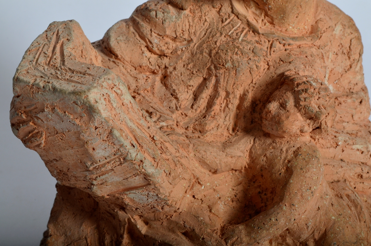 Terrakottafigur som visar ei stjande kvinne som les for eit born. Motiv frå teikning Michelangelo eller Rafael.