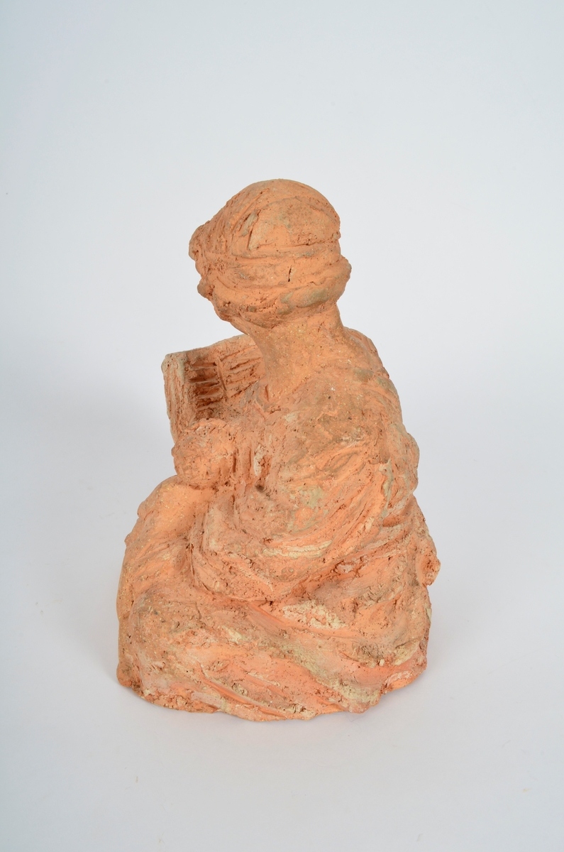 Terrakottafigur som visar ei stjande kvinne som les for eit born. Motiv frå teikning Michelangelo eller Rafael.