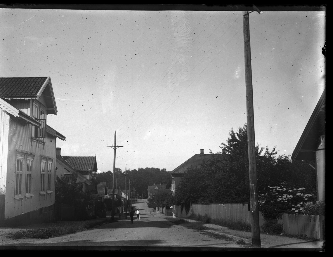 Gate med bebyggelse på hver side og barn som går mot parken.