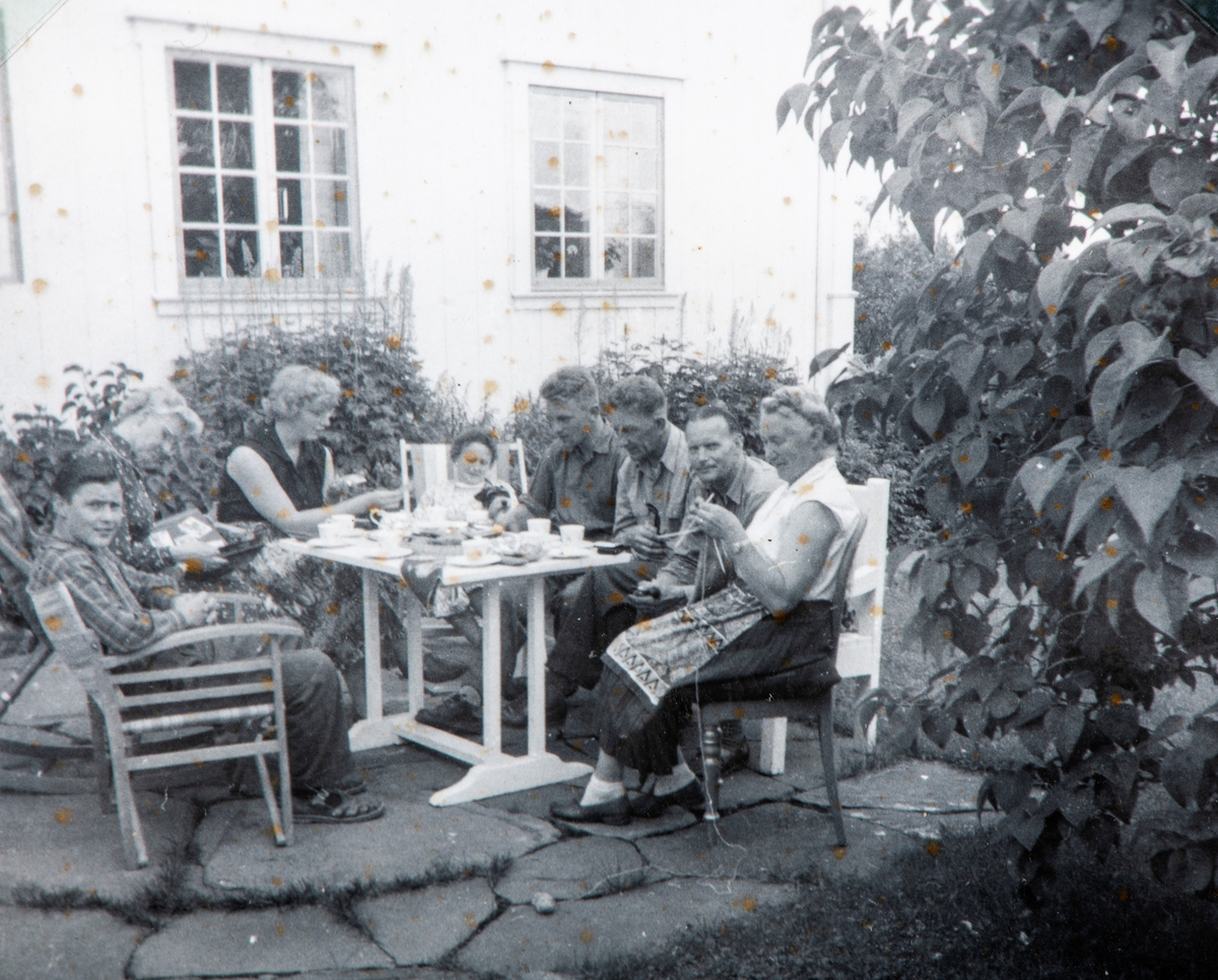 Kaffeslabras i hagen på Grylling, Løten. Lengst til høyre Oddrun Storbæk med strikketøy, mot venstre Niels Rasmussen, Ola Storbæk, Magnar Storbæk. ca midt på 1950-tallet.