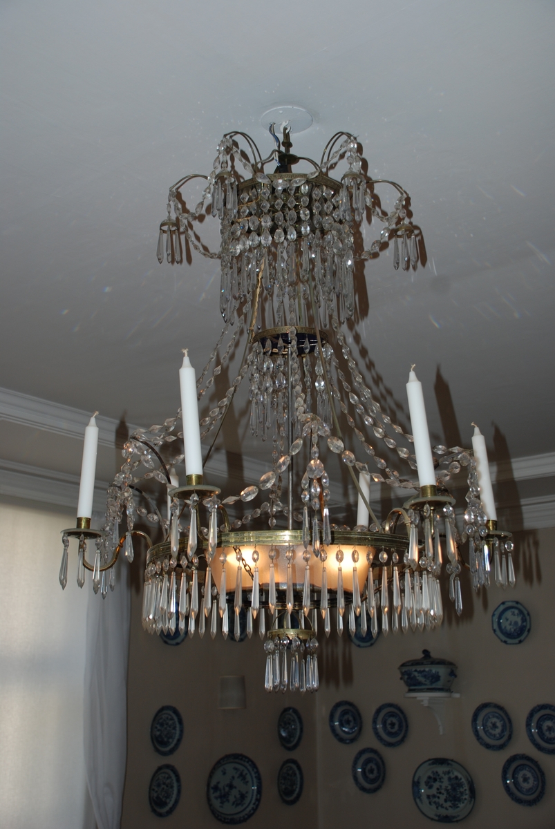 Lysekrone dekorert med prismer. Elektrisk belysning, men også med holdere til stearinlys.