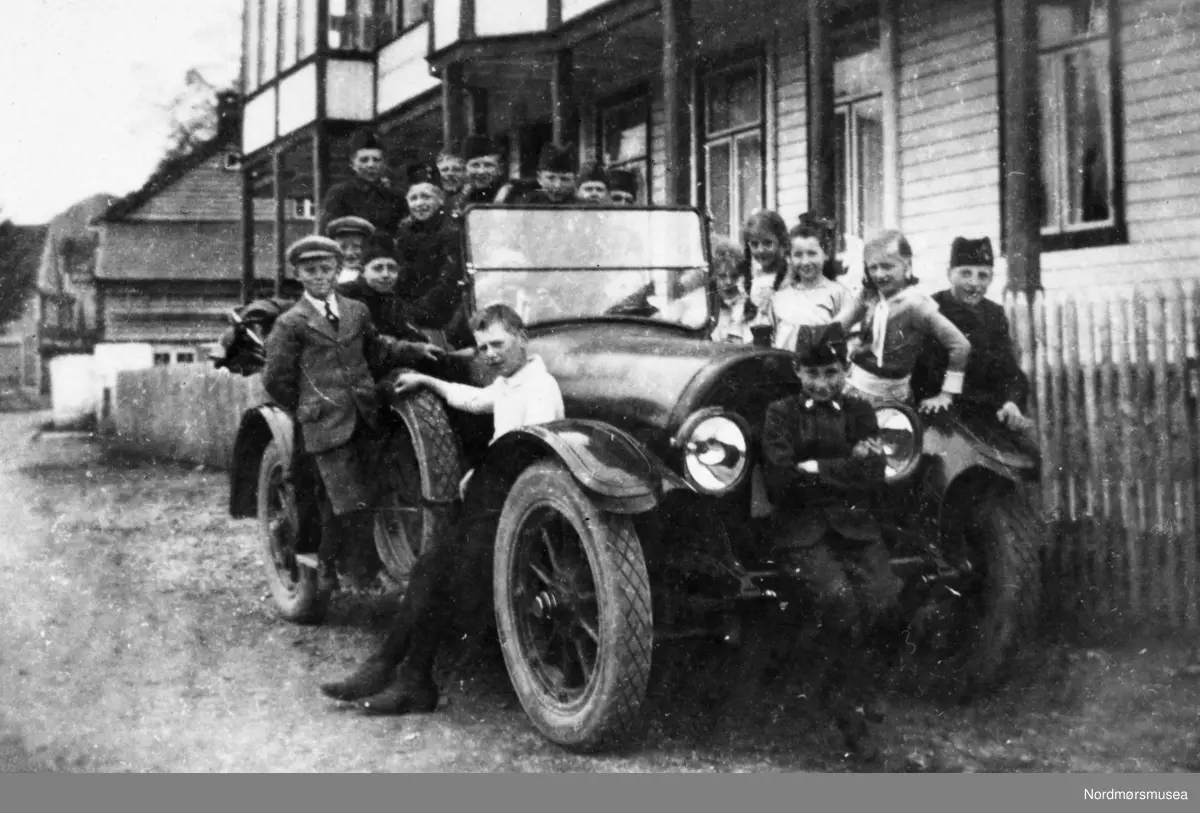 Guttemusikken i Kristiansund på tur, trolig Pinsen 1921. Her trolig fra Ørskog. Guttene ble tilbudt gratis bilturer av "fru grosserer Møller og fru Østebø fra Ålesund." Fotografier fra protokollen til Kristiansunds Guttemusikkorps i perioden 1917-1927. Protokollførere var brødrene Hans og Herlof Harstad. Protokollen er i museets privatarkiv under nr. 684. Giver av protokollen er Knut Harstad. Fra Nordmørsmusea sin fotosamling.