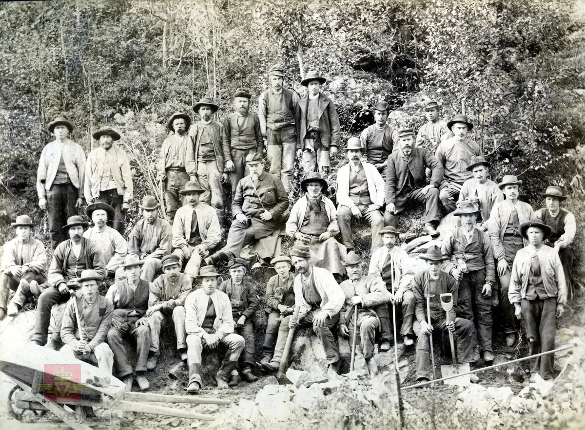 Bilde 1) I følge tidligere registrering og merking på baksiden av bildet: Arbeidslag ca. 1905 - 1915. Midt i bildet amtsingeniør Landmark sammen med Røldøler. Utlånt fra Hordaland vegkontor (Nonås)
Mest sannsynlig er det amtsingeniør Johan Peter Berg Landmark som sitter midt på bildet (med krossreim). Han var amtsingeniør i Hordaland fylke 1894 - 1919. 
Ved siden av ham til høyre på bildet sitter en smed med smedforkle.
Bilde 2 og 3) Visittkort av Johan Peter Berg Landmark, framside og bakside, i album fra "Statens veivæsens Ingeniører." 
Bilde 4 og 5)  Visittkort av Christopher Engebreth Borch, framside og bakside i album fra "Statens veivæsens Ingeniører." 
Bilde 6 og 7)  Visittkort av Hans Hagerup Krag, framside og bakside i album fra "Statens veivæsens Ingeniører." 
Bilde 8) Framside av visittkortalbum fra "Statens veivæsens Ingeniører." Statens vegvesens ingeniører ca 1859 - ca 1960.

Ref. til "Norges vegdirektører og vegsjefer," av Hans Wangensten Paus. Vedlagt informasjon fra boka, se Nedlastinger.

Gruppebildet er også gjengitt i boka "På god veg - Veghistorie i Sogn og Fjordane," av Kristin Ese, side 74, og med denne informasjon i bildeteksten:
"Vegen gjennom Haukåsgjelet vart bygd i åra 1889-1891. Her er vegarbeidarar fotograferte i samband med fint besøk, vegdirektør Hans Hagerup Krag (med krossreim, i midten)
 og amtsingeniør Christopher Engebreth Borch (med klokkekjede, i midten til høgre)." 
Foto: Ingeborg Vigdal