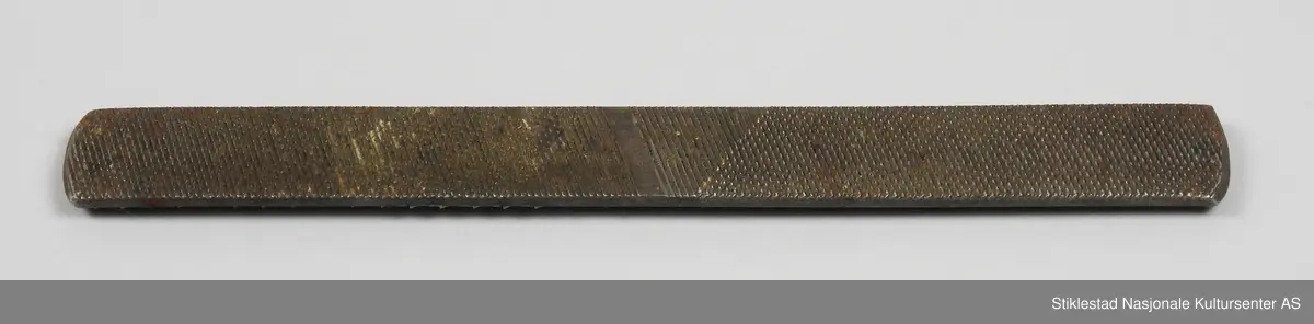 Flat rasp med buet ender. På den ene siden er fila grovt tannet (motstilt), noe finere tanning på andre siden.