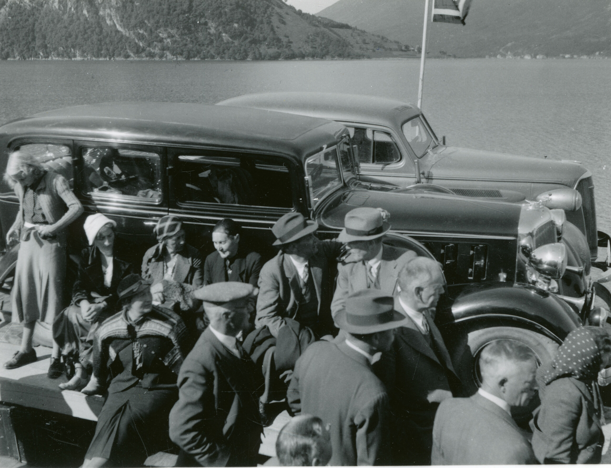 Bilar og folk på ei ferge.  Bilane: Chrysler 1932-33 (nærast ) og Chevrolet 1937.