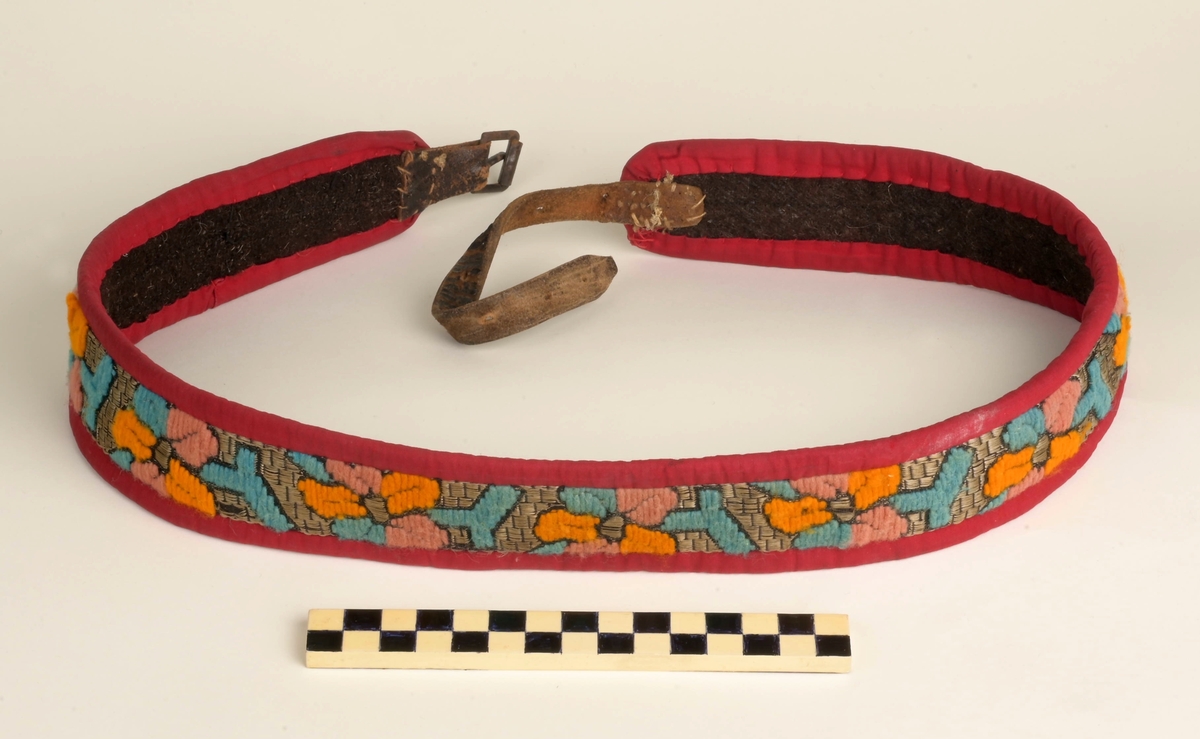 Kofte med lue, belte, forkle og sjal. Lua har dekorbånd nederst langs rimmen. Selve kofta har vevde dekorasjonsbånd på jakkeermene, kragen, oppe på og langs skuldrene, og nederst på kofta. Beltet til kofta låses ved lærreim som tres inn i lås med låsepinne - alt av stål. Selve låsen skjules av beltet da lærreim og lås er på baksiden av beltet. Beltets ende er avsluttet av tynt flettet bånd. Båndet festes i tinnknapp som er på utsiden av beltet. Dette er ei dekorativ løsning for å skjule den funksjonelle stållåsen. Forklet er blått, og dekorert med hvite snøkrystaller og blomster. Blomstene er gule, røde og blå blomser.  Kofta er i svart som er hovedfargen på kofta såvel som lua, mens dekorbånd og lue har andre farger.