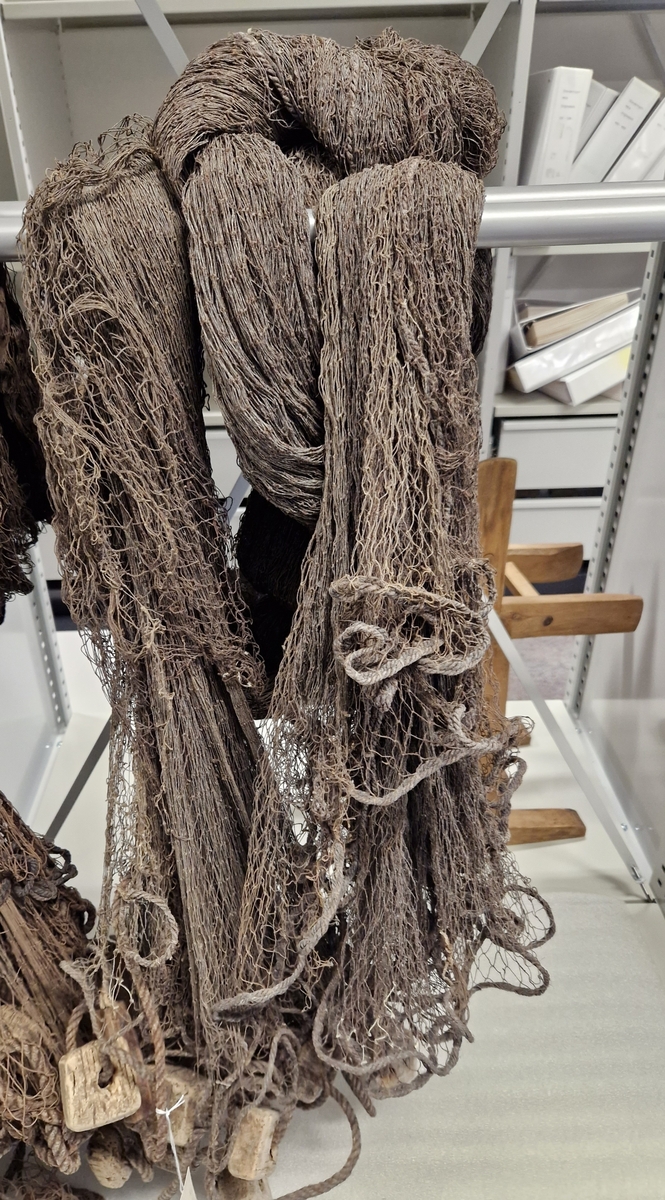 Lin og hampsnøre bunnet sammen til masker (garnlinet), påfestet korkebiter og gjennomhulete trebiter med innskåret bokstaver og tall
