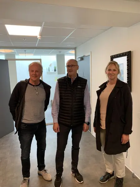 To menn og en kvinne stående inne i kontorgang