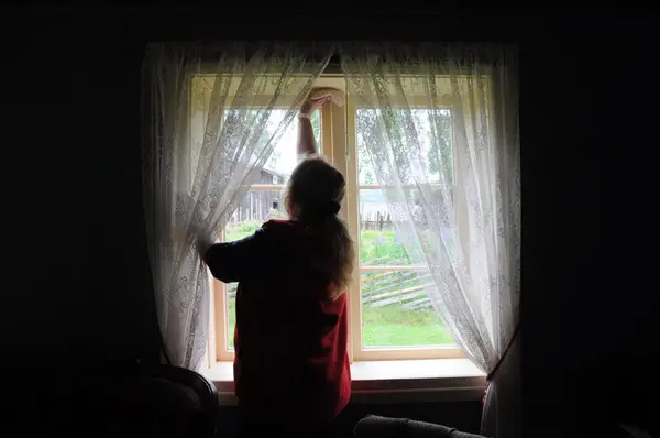 Kvinne som tørker støv rundt eit vindauge