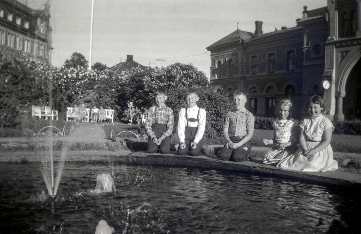 Klassekamerater fra Farmen skole i Vang på skoletur til Hamar. Her sittende rundt fontenen i jernbaneparken nede ved stasjonen. Til venstre: Sven Bakken, Magne Henriksen, Henning Sørlie, Eli Vesaas, født Glærum, Marit Synnøve Sveum, født Kristiansen.