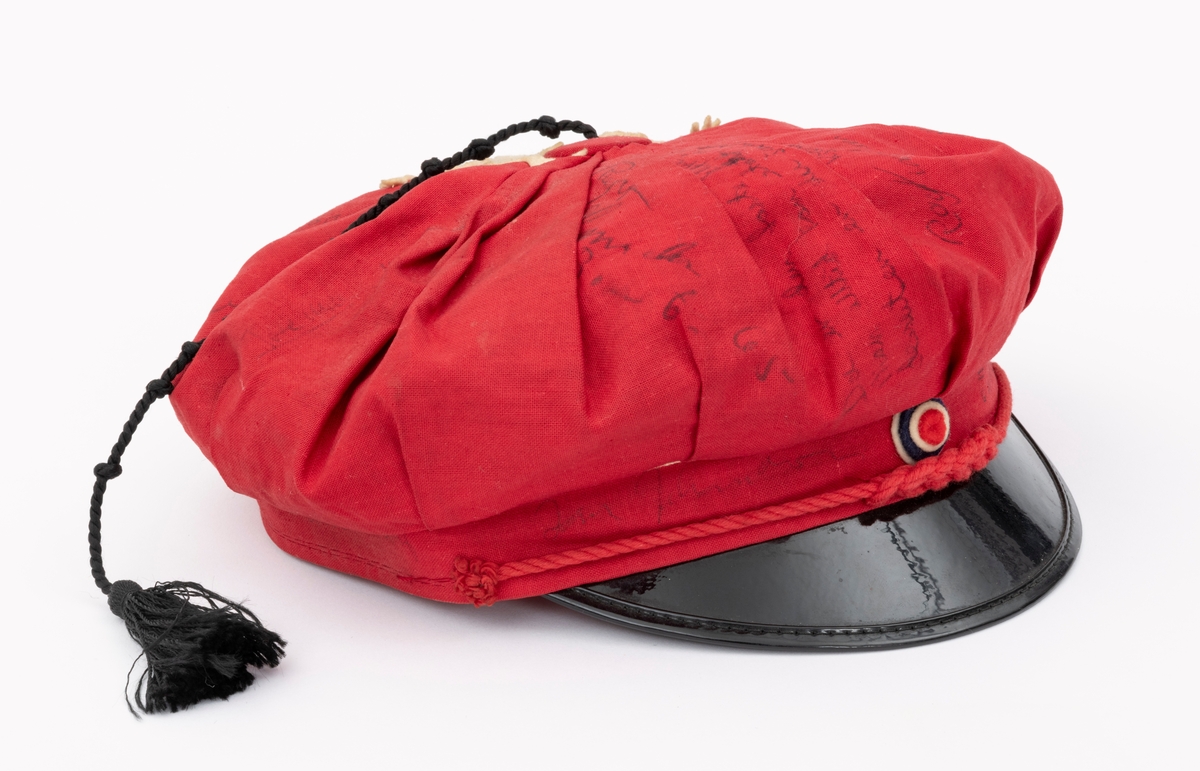 Rød russelue med slagord og autografer av blant annet jazzmusikerne Karin Krog og Jan Johansson m.f. påskrevet på lua. En hvit frosk i filt er limt på. Frosken er i følge giver Tone Marie Buberg logoen til Grorud høyere allmennskole.
Flere knuter i snora til dusken.