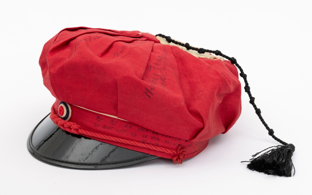 Rød russelue med slagord og autografer av blant annet jazzmusikerne Karin Krog og Jan Johansson m.f. påskrevet på lua. En hvit frosk i filt er limt på. Frosken er i følge giver Tone Marie Buberg logoen til Grorud høyere allmennskole.
Flere knuter i snora til dusken.