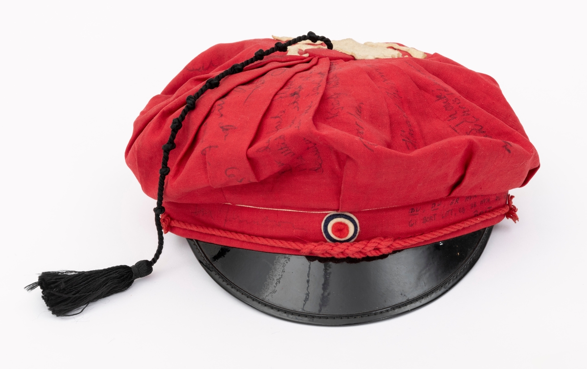 Rød russelue med slagord og autografer av blant annet jazzmusikerne Karin Krog og Jan Johansson m.f. påskrevet på lua. En hvit frosk i filt er limt på. Frosken er i følge giver Tone Marie Buberg logoen til Grorud høyere allmennskole.
Flere knuter i snora til dusken.