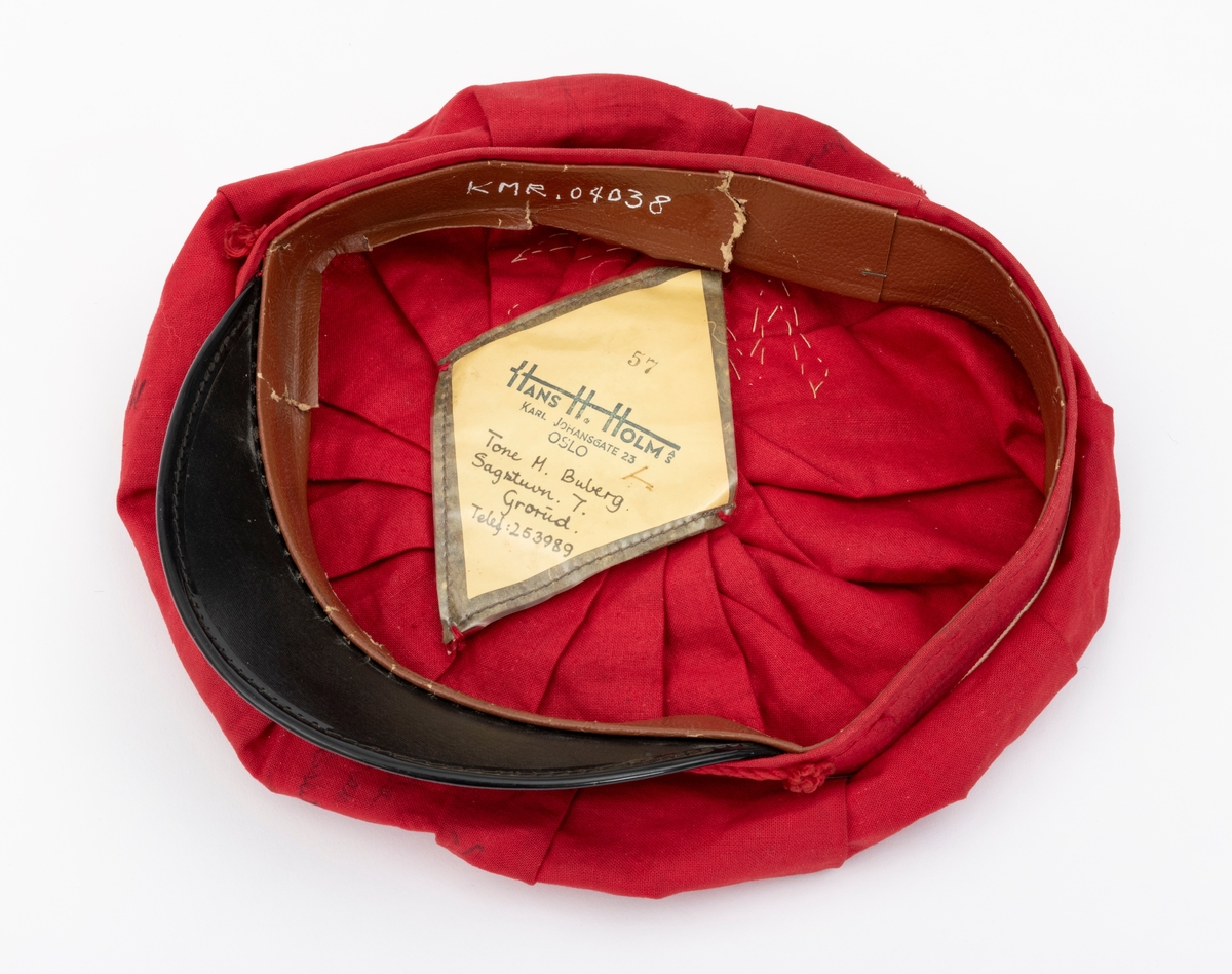 Rød russelue med slagord og autografer av blant annet jazzmusikerne Karin Krog og Jan Johansson m.f. påskrevet på lua. En hvit frosk i filt er limt på. Frosken er i følge giver Tone Marie Buberg logoen til Grorud høyere allmennskole.
Flere knuter i snora til dusken.