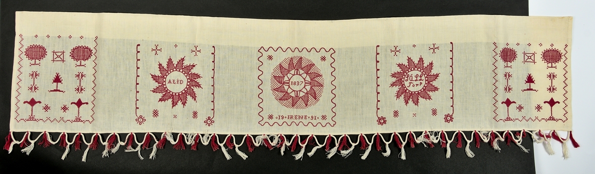 Vit gardin i linnetyg, med hallandsbroderi. Broderiet består av 5 delar. De tre centrala innehåller texterna ”ALID”, ”1837 19 IRENE 91” och ”Sälltorp”. I nedre delen av gardinen finns fransar i rosa och vitt. Dessa fransar är fastknutna på ett grövre bomullssnöre.  

Längd: 143 cm
Bredd: 30 cm + 7 cm frans
