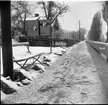 Vinterlandskap. Bredvid en snömoddig väg står en skylt som indikerar platser för bilparkering. Det är riksvägen som brukar kallas för riksettan.  Fotot taget mot söder till Gränna centrum.