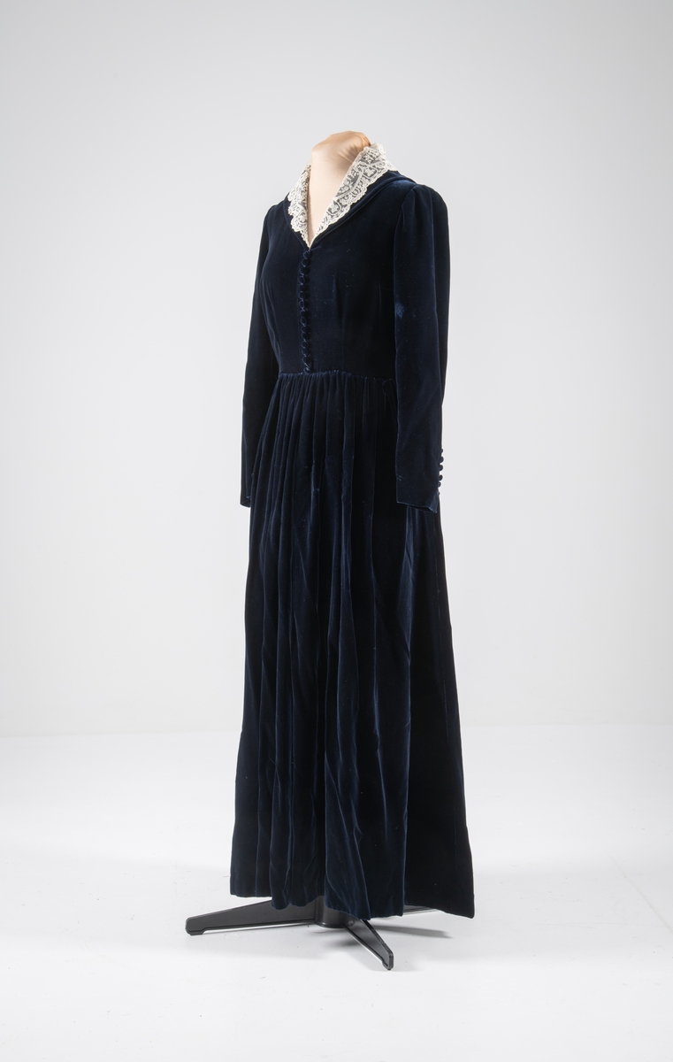 Den mørkeblå kjolen er datert til 1930-årene. Den ble sydd for Hedvig Sverdrup-Thygeson.
Det fortelles at kjolen er laget av den første viskosefløyelen produsert av cellulose fra trevirke som kom fra trevarebedriften Stangeskovene. Hedvig Sverdrup-Thygesons mann var aksjonær i Stangeskovene, og alle aksjonærkonene fikk noen meter av dette stoffet. Det er en sterk familiær tilknytning til Stangeskovene da selskapets grunnlegger, Nils Anker Stang, var Hedvigs morfar.
Ifølge etterkommere av kjolens første eier er kragen laget av italienske kniplinger.
