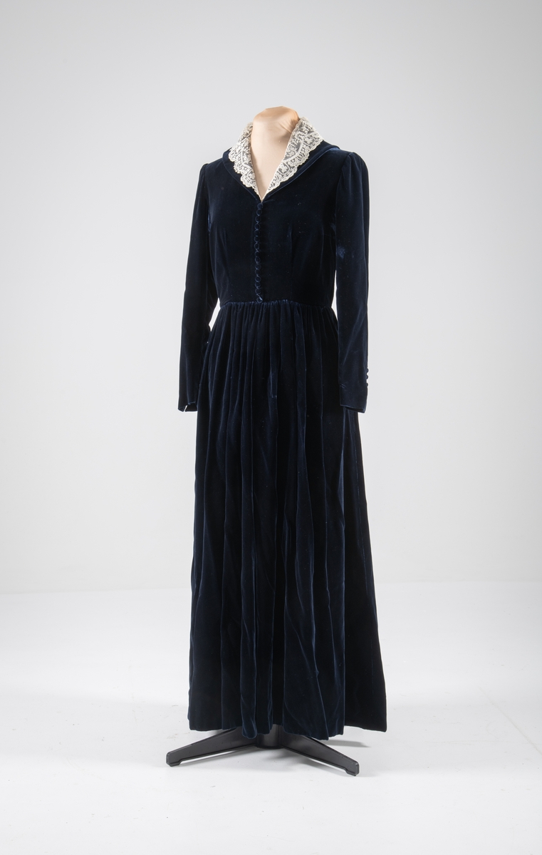 Den mørkeblå kjolen er datert til 1930-årene. Den ble sydd for Hedvig Sverdrup-Thygeson.
Det fortelles at kjolen er laget av den første viskosefløyelen produsert av cellulose fra trevirke som kom fra trevarebedriften Stangeskovene. Hedvig Sverdrup-Thygesons mann var aksjonær i Stangeskovene, og alle aksjonærkonene fikk noen meter av dette stoffet. Det er en sterk familiær tilknytning til Stangeskovene da selskapets grunnlegger, Nils Anker Stang, var Hedvigs morfar.
Ifølge etterkommere av kjolens første eier er kragen laget av italienske kniplinger.
