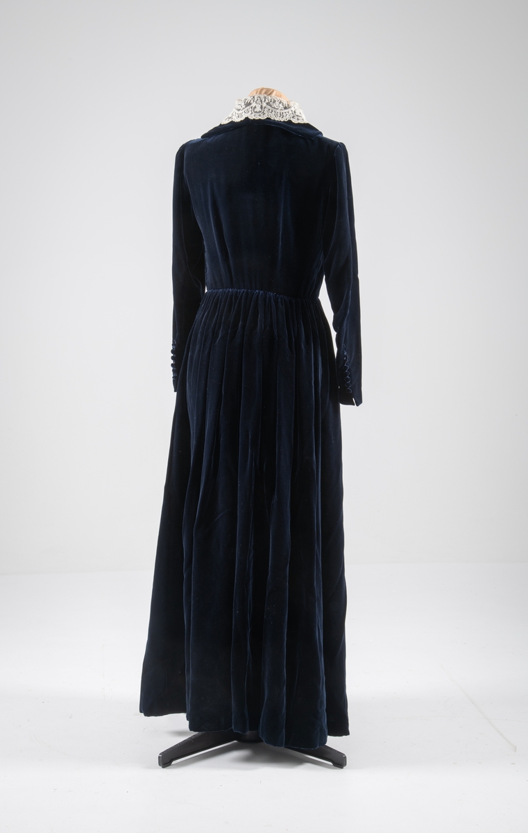 Den mørkeblå kjolen er datert til 1930-årene. Den ble sydd for Hedvig Sverdrup-Thygeson.
Det fortelles at kjolen er laget av den første viskosefløyelen produsert av cellulose fra trevirke som kom fra trevarebedriften Stangeskovene. Hedvig Sverdrup-Thygesons mann var aksjonær i Stangeskovene, og alle aksjonærkonene fikk noen meter av dette stoffet. Det er en sterk familiær tilknytning til Stangeskovene da selskapets grunnlegger, Nils Anker Stang, var Hedvigs morfar.
Ifølge etterkommere av kjolens første eier er kragen laget av italienske kniplinger.
